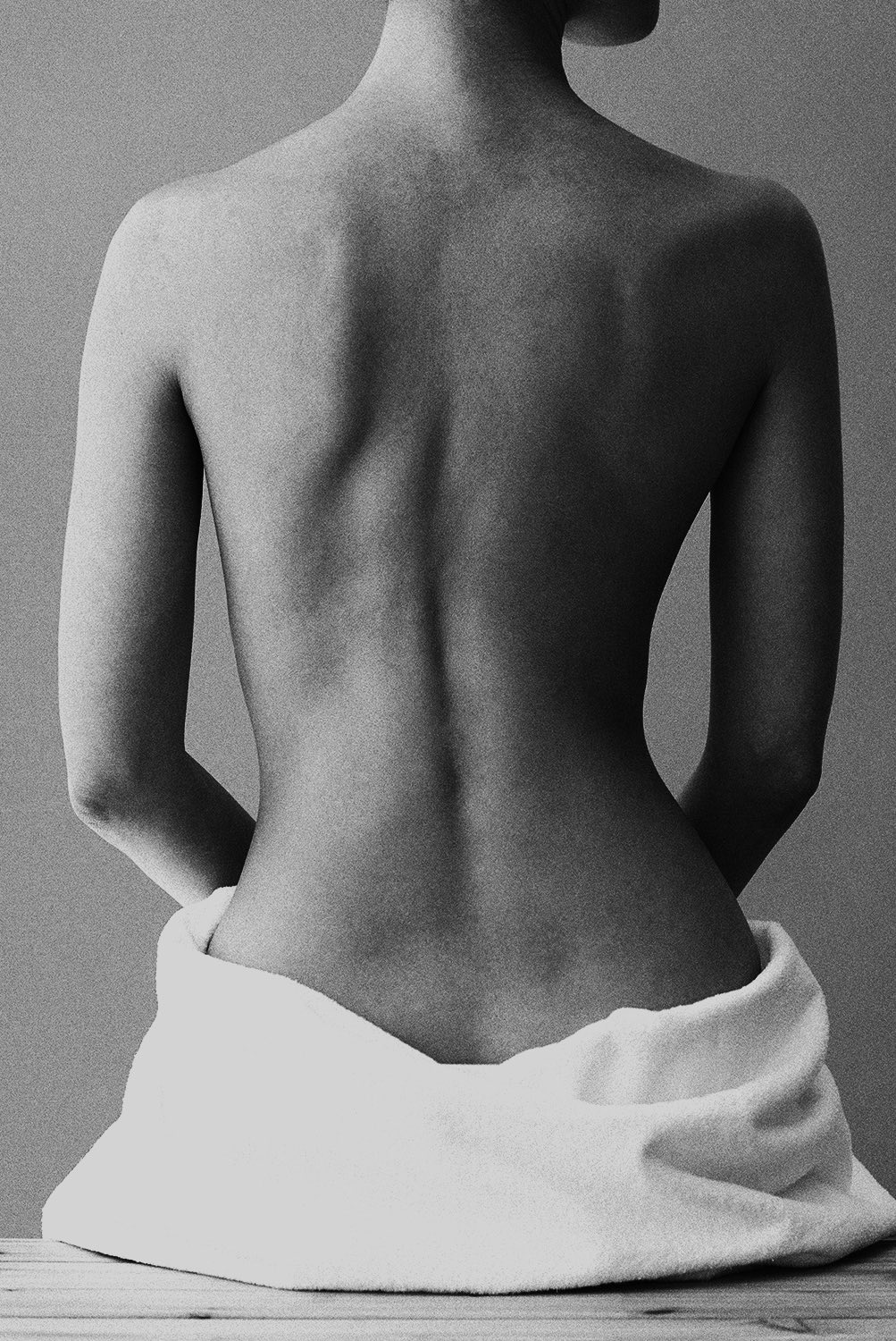 photo en noir et blanc d'une femme nue de dos avec une serviette autour de la taille